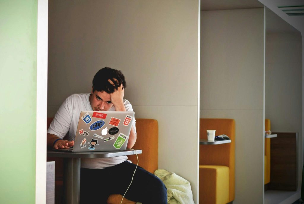 Eine Person sitzt an einem Tisch mit einem Laptop, den Kopf stützend, in einer nachdenklichen oder gestressten Haltung. Das Bild vermittelt das Gefühl von Konzentration oder Überforderung. Keywords: Stressbewältigung, CMD und psychische Belastung, Angstzustände durch Schmerzen, Arbeiten mit CMD.