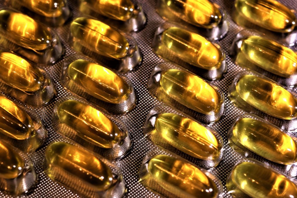 Eine Nahaufnahme von goldenen Omega-3-Fettsäuren-Kapseln – Nahrungsergänzung zur Unterstützung der Entzündungshemmung und Muskelentspannung bei CMD. Keywords: Omega-3-Fettsäuren, Nahrungsergänzung, CMD-Ernährung.