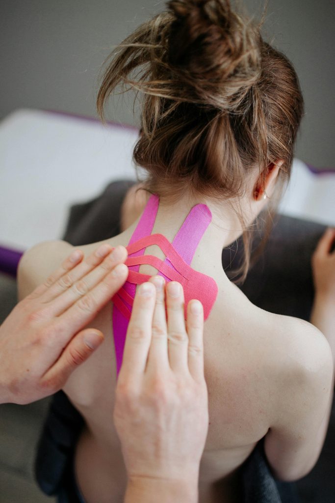 Eine Patientin mit Tape-Anwendungen im Nackenbereich. Diese Technik wird häufig in der manuellen Therapie bei CMD eingesetzt, um Verspannungen zu lösen und die Haltung zu verbessern. Manuelle Techniken in Kombination mit Tape können Nacken- und Kieferbeschwerden effektiv lindern.