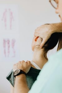 Osteopath behandelt den Nackenbereich einer Patientin mit sanften Griffen, um Blockaden zu lösen und die Beweglichkeit zu fördern. Diese osteopathische Technik wird häufig bei CMD-Patienten eingesetzt, die unter Nackenverspannungen und Kieferproblemen leiden.