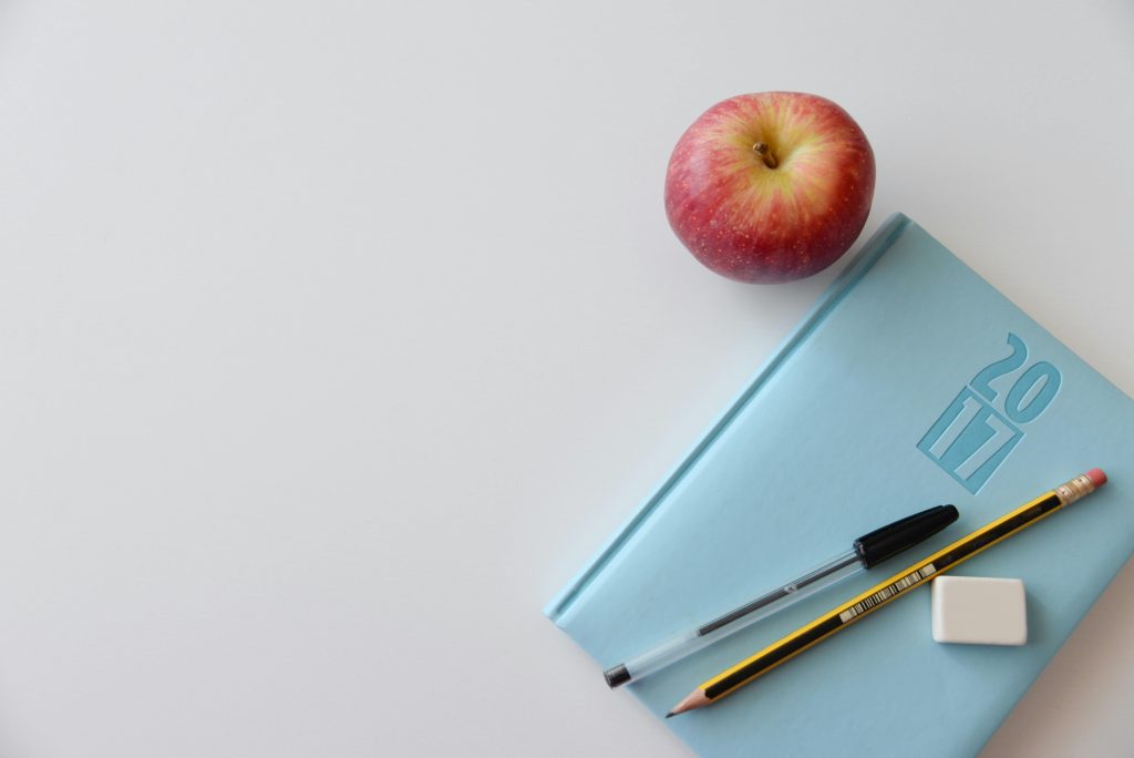 Ein geöffnetes Notizbuch mit Stift, Apfel und Radiergummi symbolisiert Wissen und Vorbereitung – ein wichtiger Bestandteil der Psychoedukation bei CMD.