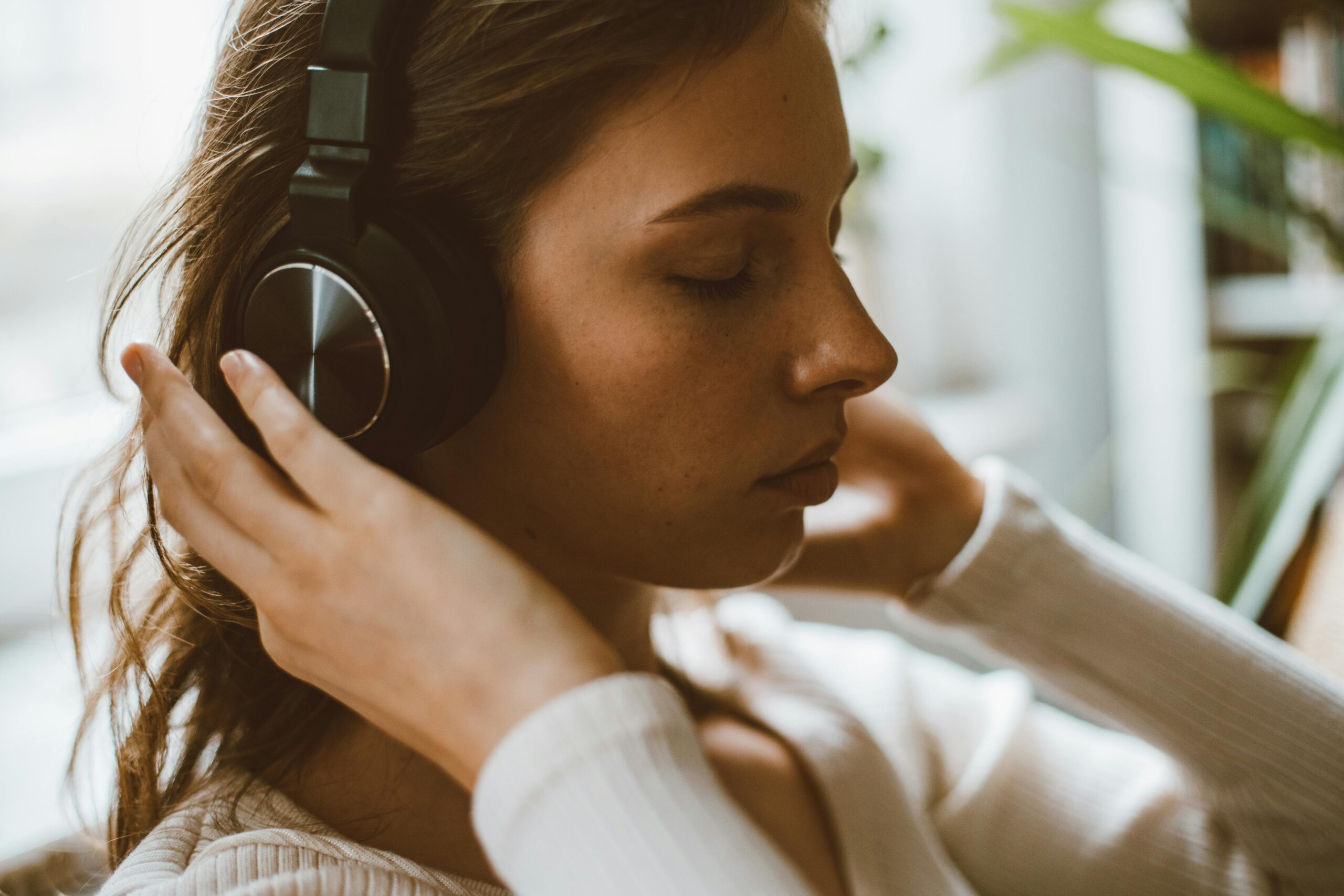 Eine Frau hört entspannende Musik über Kopfhörer, um Stress abzubauen und die mentale Balance zu fördern. Musiktherapie kann bei CMD helfen, Verspannungen zu lösen und das Wohlbefinden zu steigern.