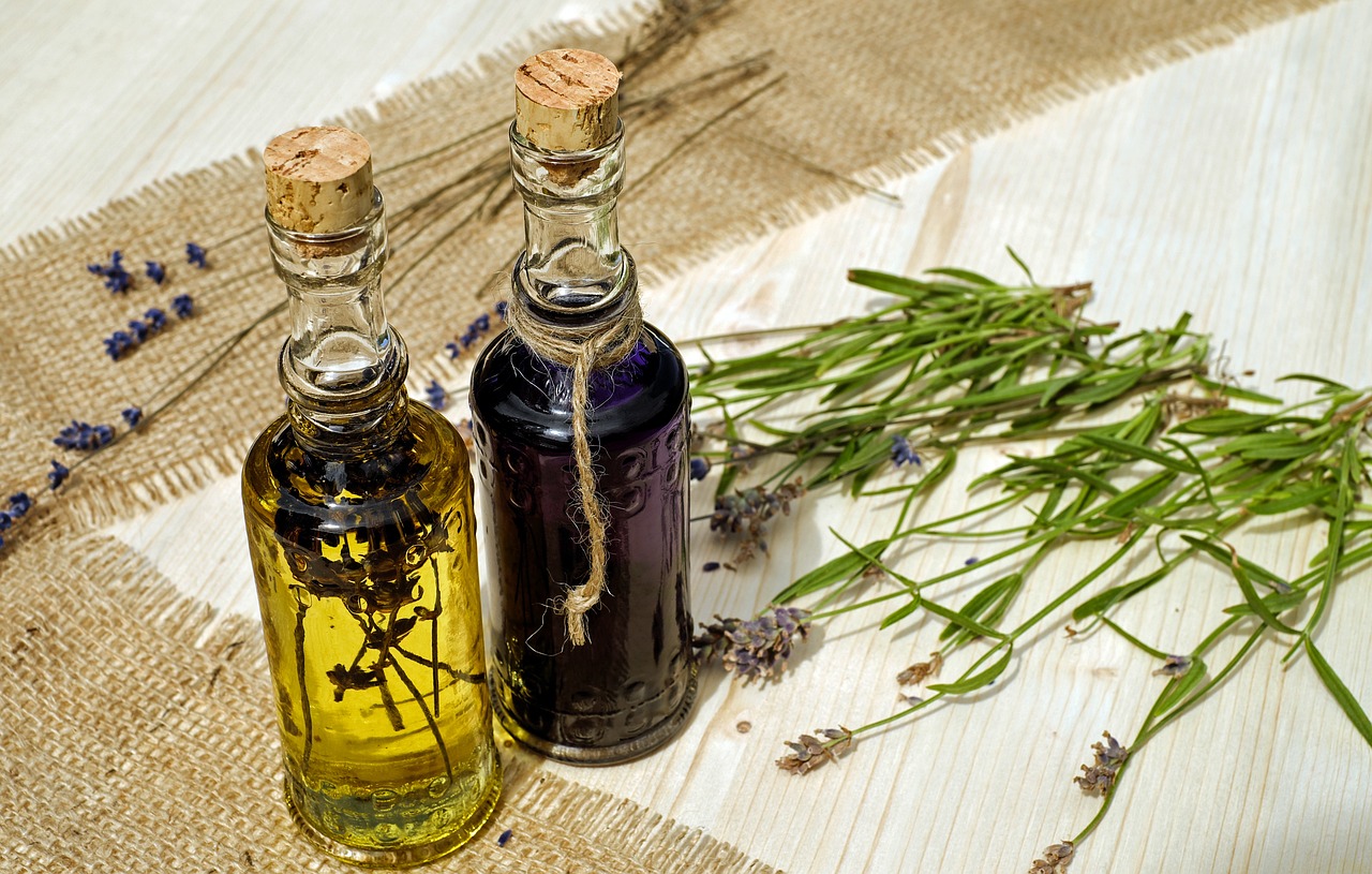 Zwei dekorative Flaschen mit ätherischen Ölen stehen auf einem Tisch, umgeben von getrocknetem Lavendel. Ätherische Öle wie Lavendelöl werden in der Naturheilkunde häufig zur Entspannung und Stressreduktion bei CMD eingesetzt.