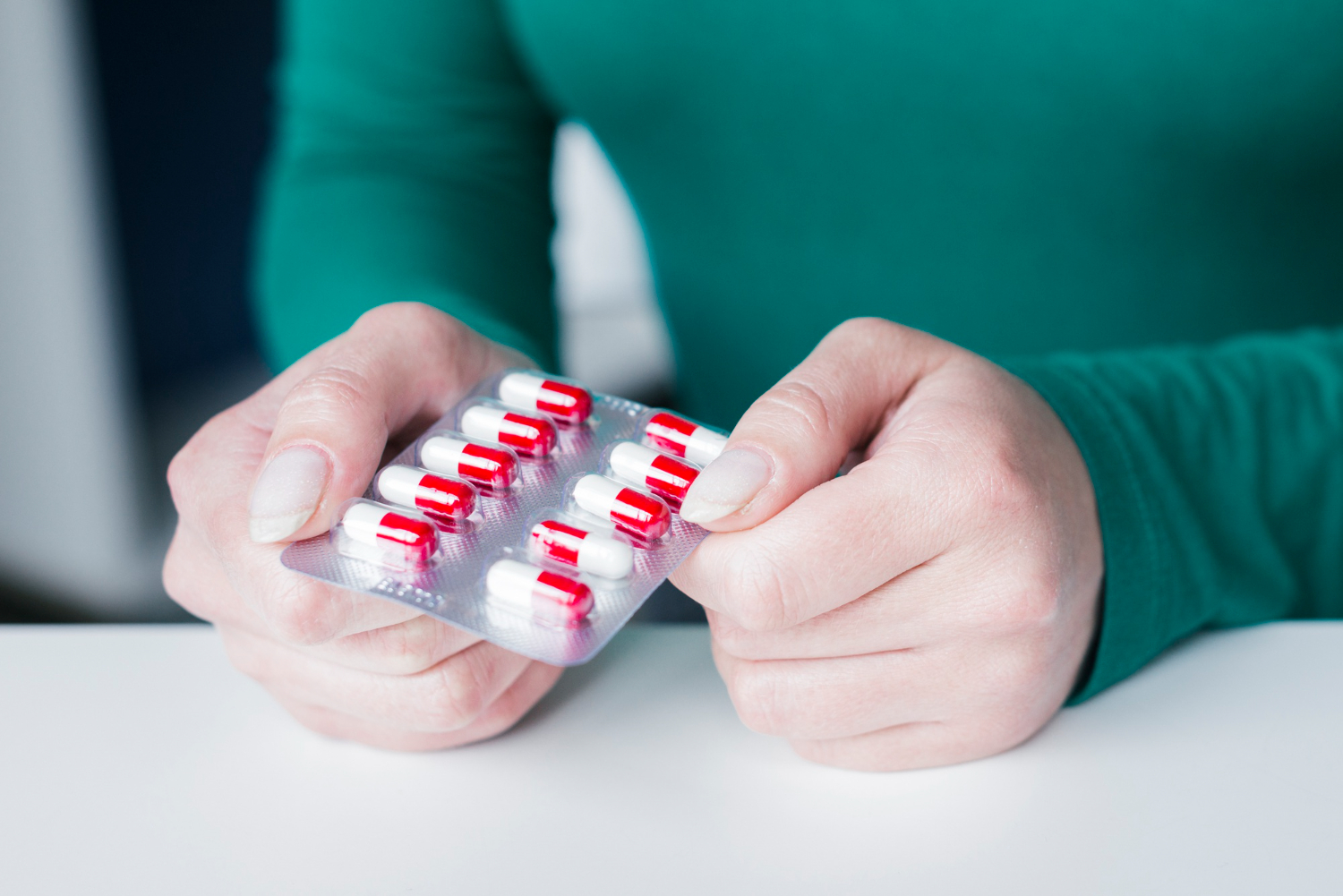 Das Bild zeigt eine Hand, die eine Blisterpackung mit roten und weißen Kapseln hält. Es veranschaulicht die individuelle Auswahl von Schmerzmitteln unter ärztlicher Beratung, die für CMD-Patient*innen essenziell ist.