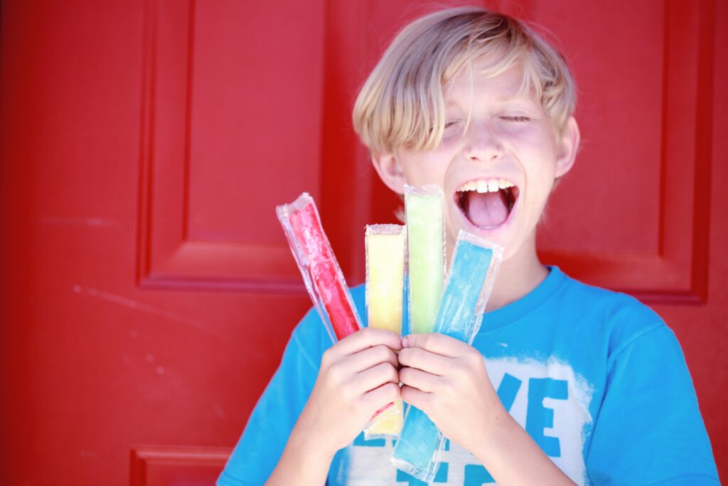 Lachender Jugendlicher mit Eis am Stiel – Symbolbild für unbeschwertes Jugendalter trotz möglicher Kieferprobleme wie CMD.