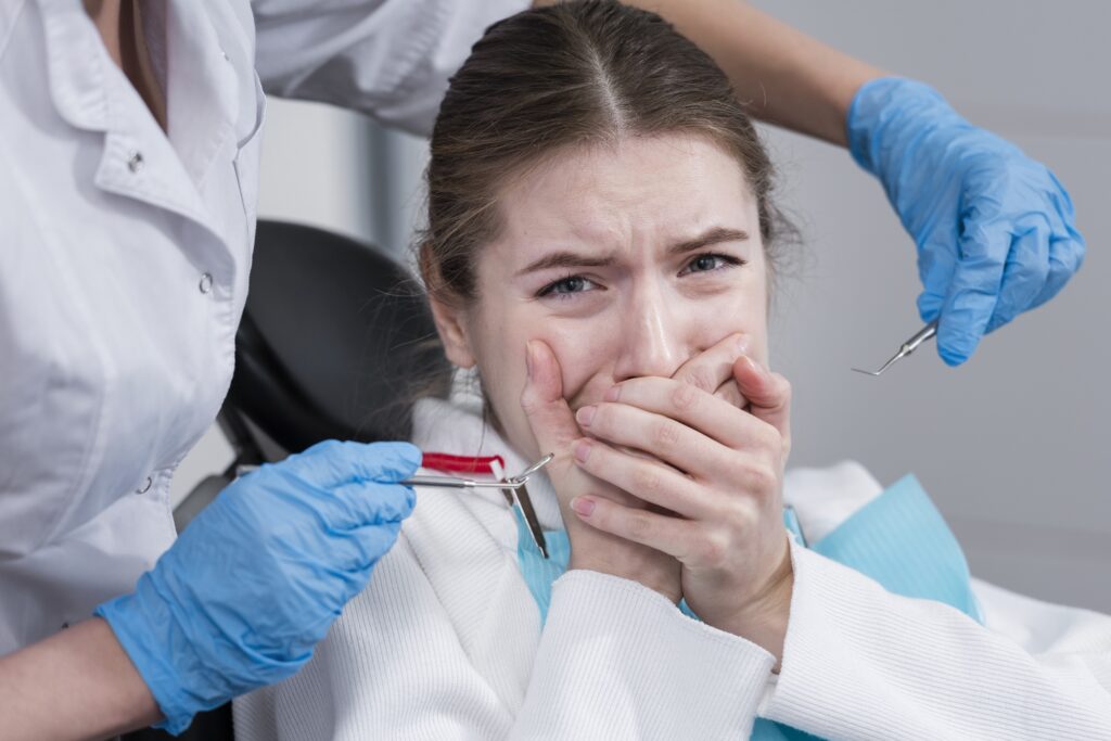 Patientin mit Panik im Zahnarztstuhl hält sich erschrocken den Mund – starke Zahnarztphobie als möglicher Auslöser für CMD-Beschwerden.